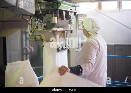 14 october 2014.Ukraine.Kyiv. The woman of average years in a white dressing gown works on a conveyor at factory of times of the Soviet, manual skills Stock Photo