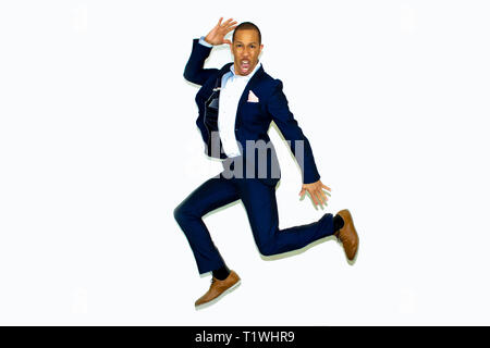 smart mixed race man jumping for joy in an electric blue suit Stock Photo