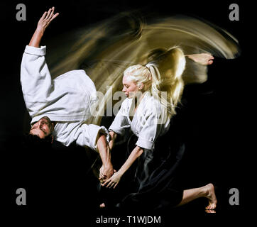 two budokas fighters man and woman practicing Aikido studio shot isolated on black background Stock Photo