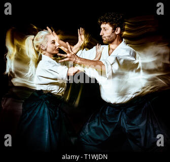 two budokas fighters man and woman practicing Aikido studio shot isolated on black background Stock Photo