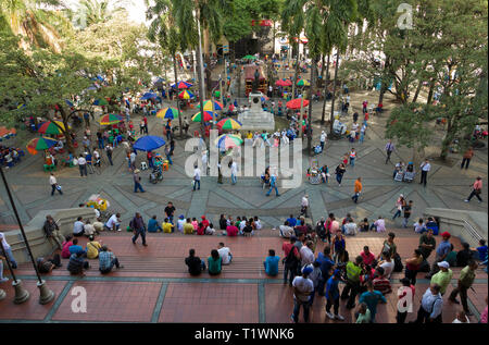 Colombia: Medellin. Crowd of inhabitants and tourist in the shade of trees in a square of the city Stock Photo