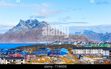 Inuit houses and cottages scattered across tundra landscape in residential suburb of Nuuk city with fjord and mountains in the background, Greenland Stock Photo