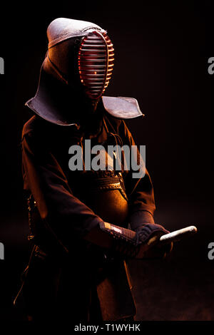 Kendo fighter in armor and helmet standing on black Stock Photo