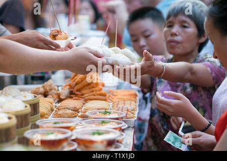 Wangfujing street, Beijing, China - 08 01 2016:Woman buying street food in Wangfujing street, a shopping street in Beijing, China Stock Photo