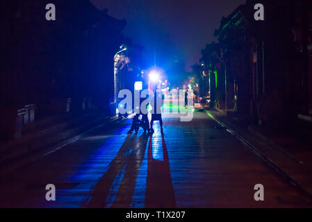 Pingyao, China - 08 13 2016: Silhouette and shadow of people in the alley in the night in city center. Lights in Pingyao at night. Pingyao, Shanxi, Ch Stock Photo