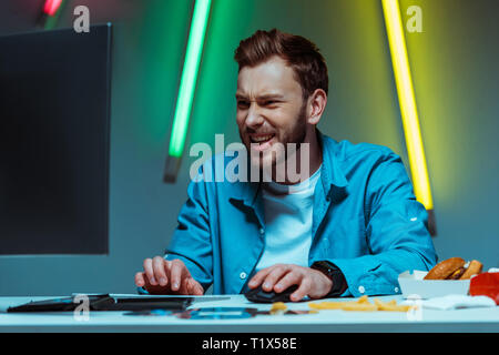 handsome and happy man playing video game with computer mouse and keyboard Stock Photo