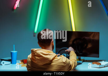 back view of man playing video game with steering wheel Stock Photo