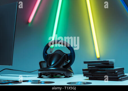 selective focus of steering wheel and compact disks with video games on table Stock Photo