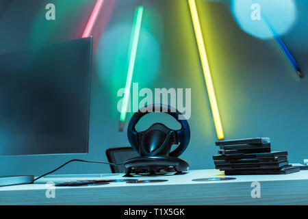 computer monitor, steering wheel and compact disks with video games on table Stock Photo