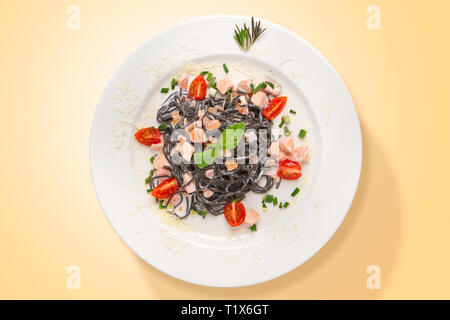 Italian squid ink pasta with salmon and parmesan cheese served in a white plate. Top view. Food from above Stock Photo