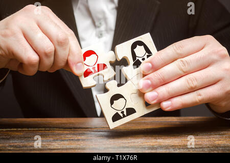 A businessman collects puzzles symbolizing a team of employees. The concept of the organization of the team and the business hierarchy. Management. Th Stock Photo