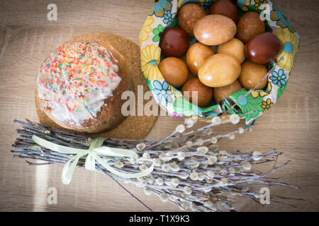 Table before Easter decorated with Easter cake, willow and eggs painted with onion peel Stock Photo