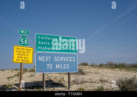 Taft, California - March 25, 2019: Road signs warn drivers of desolate conditions - next services 70 miles, no tractors or semis, on California State  Stock Photo