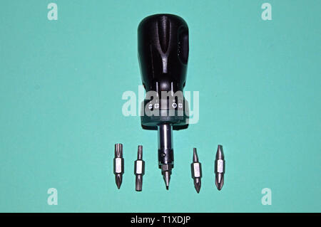 Various bits in a row in the bit holder. Bits for screwdrivers on the white surface. Cross bits. Flat-blade bits. Screw and unscrew fasteners Stock Photo