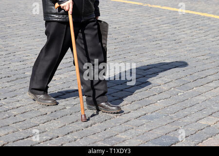 Old man walking with a cane on a street. Concept for disability, old age, limping person, diseases of the spine, elderly people Stock Photo