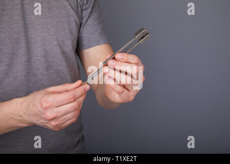 Tuning Fork for hearing tests in hands of young man. Medical equipment of otolaryngologist (ENT). Medical and Healthcare concept. Stock Photo