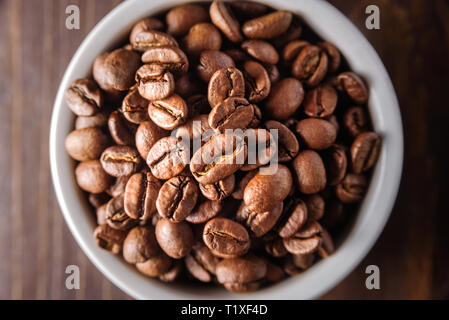 Coffee beans and ground coffee in ceramic bowls on dark wooden background Stock Photo
