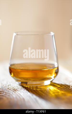 Sniffer glass with whiskey on wooden table in sunlight Stock Photo