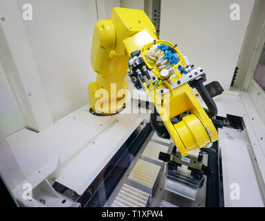 Bochum, North Rhine-Westphalia, Germany - Robot arm equips a CNC milling machine with workpieces here at Stromboli Elektro und Feinwerktechnik on the  Stock Photo