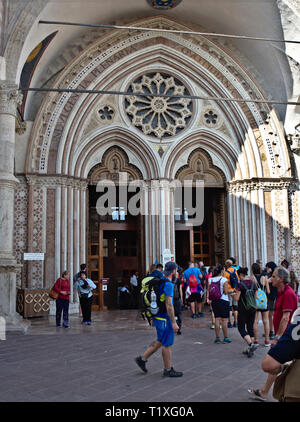 Assisi Umbria Italia, Italy. The entrance portal of the lower Basilica of Saint Francis (Basilica Inferiore di San Francesco d'Assisi), pilgrims Stock Photo
