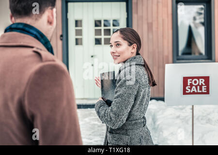 Real estate agent inviting her client to enter the house and look at it Stock Photo
