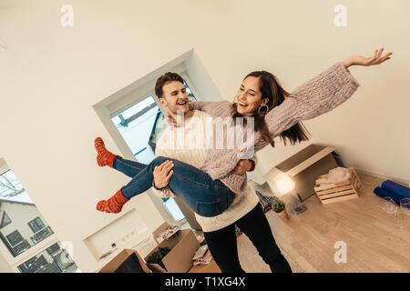 Loving man wearing white sweater caring his wife in hands Stock Photo