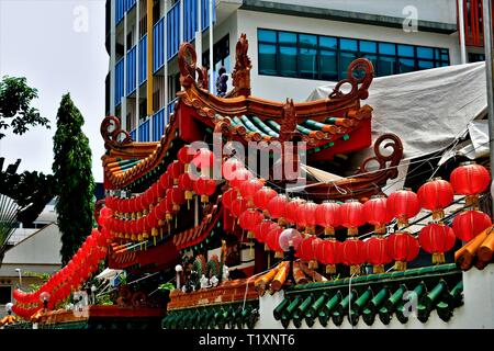 Traditional Buddhist temple with strings of red Chinese lanterns and strong architectural detail in historic Geylang, Singapore Stock Photo