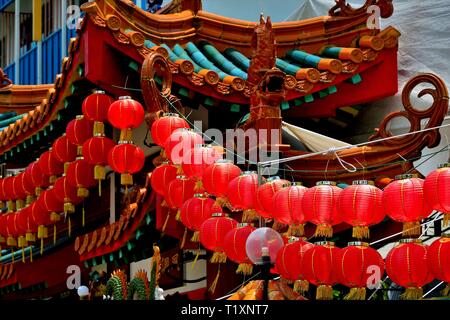 Traditional Buddhist temple with strings of red Chinese lanterns and strong architectural detail in historic Geylang, Singapore Stock Photo