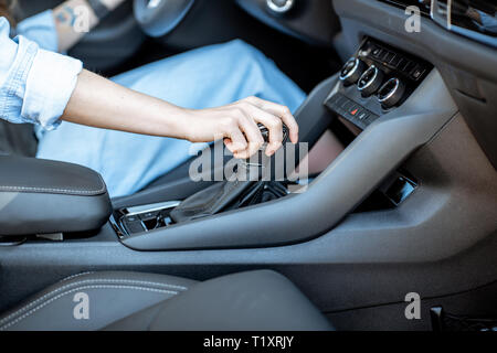 Woman switching gear, holding handle of the automatic gearbox of the modern car, close-up view Stock Photo