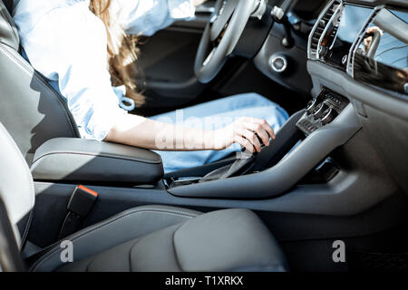 Woman switching gear, holding handle of the automatic gearbox of the modern car Stock Photo