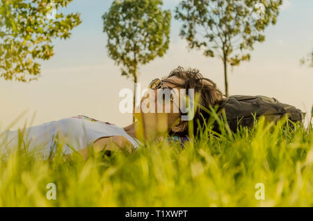 Pretty brunette woman relaxing on grass on a sunny day. Daydreaming concept. Stock Photo