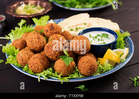 Falafel, hummus and pita. Middle eastern or arabic dishes on a dark background. Halal food. Stock Photo