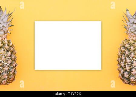 Pineapples lie on the edges of the orange background. In the center is a white blank sheet for writing text. Template on the theme of health or health Stock Photo