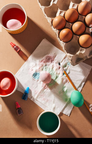 Open packaging with chicken eggs, new watercolor paints, brushes on packaging paper. Set for easter punishment. Stock Photo