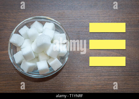 Top view of sugar cubes in a glass bowl on a wooden background. Copy space provided. Text space for writing disadvantages of sugar. Diabetes caused by Stock Photo