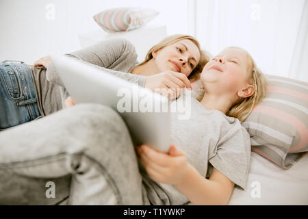 Young mother and her little daughter at home at sunny morning. Soft pastel colors. Happy family time on weekend. Mother's Day concept. Family, love, lifestyle, motherhood and tender moments concepts. Stock Photo