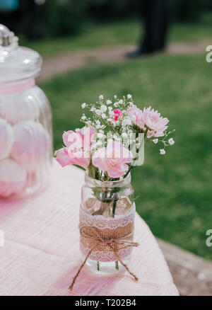 Pink flowers in decorated glass on pink table, sweets, on green background. Concept woman's or mother's day Stock Photo