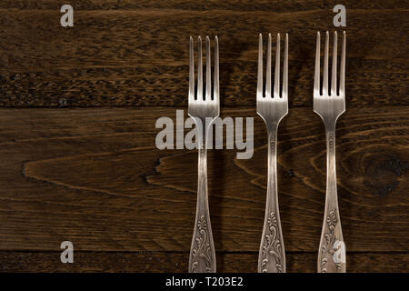 three vintage forks on a wooden table, view from the top Stock Photo