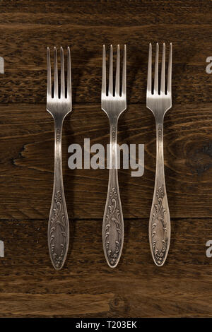 three vintage forks on a wooden table, view from the top Stock Photo