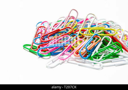 A lot of multi-colored stationery clips for documents lie on a white background. Close-up Stock Photo