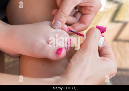 Mother painting nails of his little daughter. Fun activity at home, girl birthday party, spring and summertime. Stock Photo