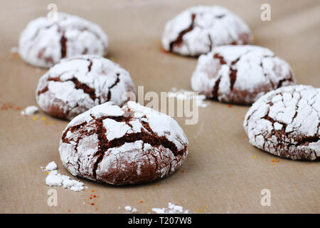 Chocolate cookies with cracks on baking paper and iolated on black. Cracked chocolate biscuits. Stock Photo