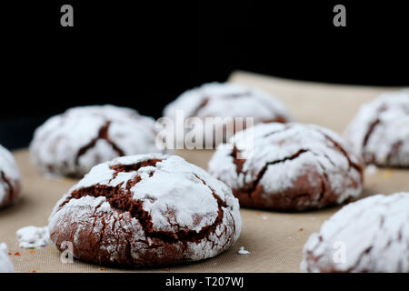 Chocolate cookies with cracks on baking paper and iolated on black. Cracked chocolate biscuits. Stock Photo