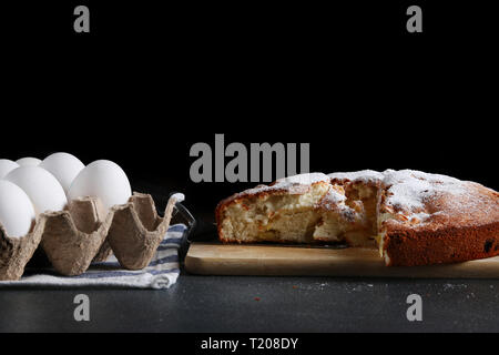sliced pie and ingredients for making on dark background. Stock Photo