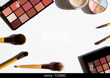 Bright arrangement of make up cosmetics and accessories. Eyeshadow palettes, powder, concealer and natural brushes with bamboo wood handles. Copy spac Stock Photo