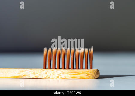 Bamboo tooth brush on white surface under bright sun light. Stock Photo