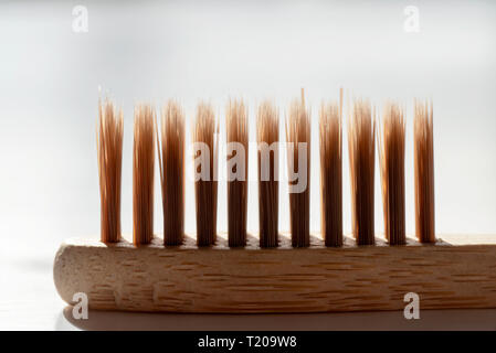 Bamboo tooth brush on white surface under bright sun light. Stock Photo