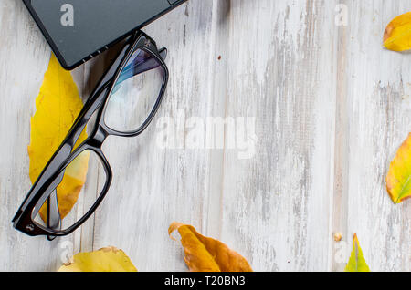 White office desk workspace with Laptop, glasses and yellow leaves on white background. Flat lay, top view, mockup. Stock Photo