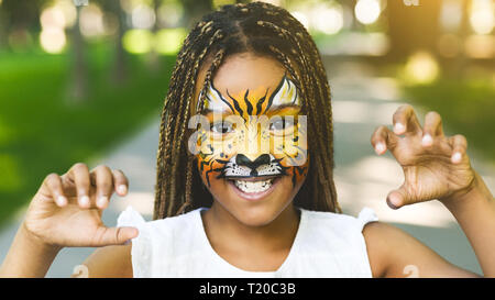 Adorable african-american girl with creative face painting roaring Stock Photo