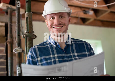 Portrait Of Architect Inside House Being Renovated Studying Plans Stock Photo